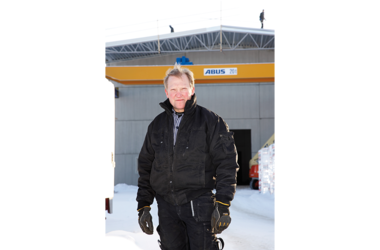 Employee standing in front of an industrial hall where an ABUS double girder overhead travelling crane ZLK can be seen in the background