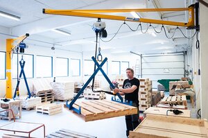 Employee operates wall jib crane in workshop for the disabled in Norway