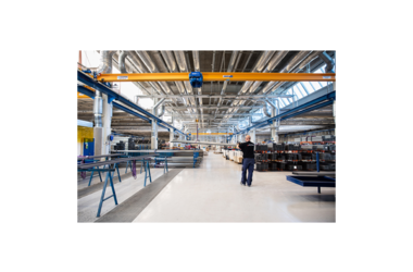 Employee works with single girder travelling crane in production hall